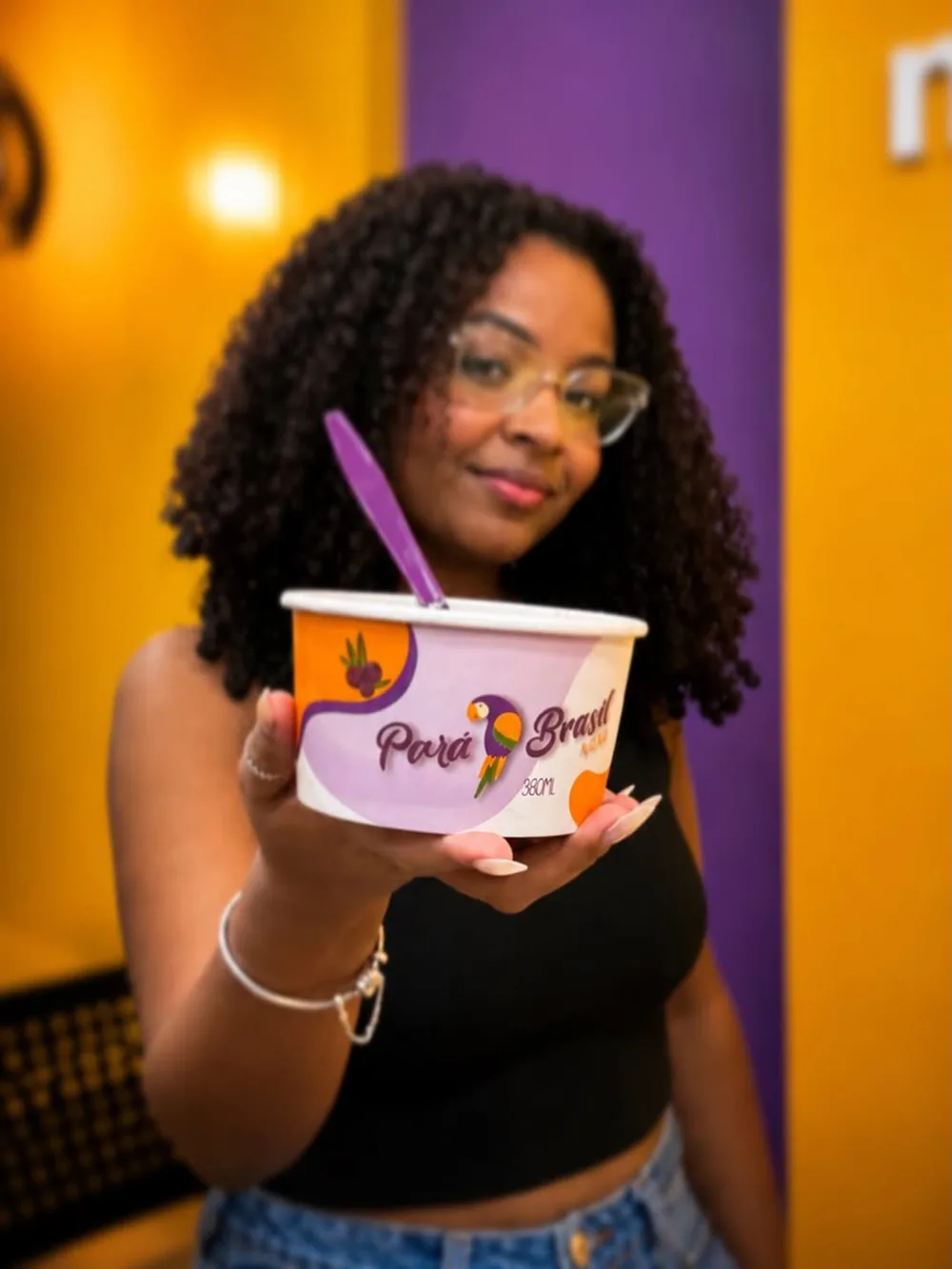 Cliente com pote de açaí no ambiente roxo do ParáBrasil